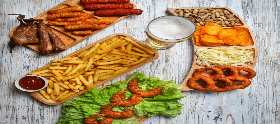 Mesa com diversos alimentos ultraprocessados, como batatas fritas, an